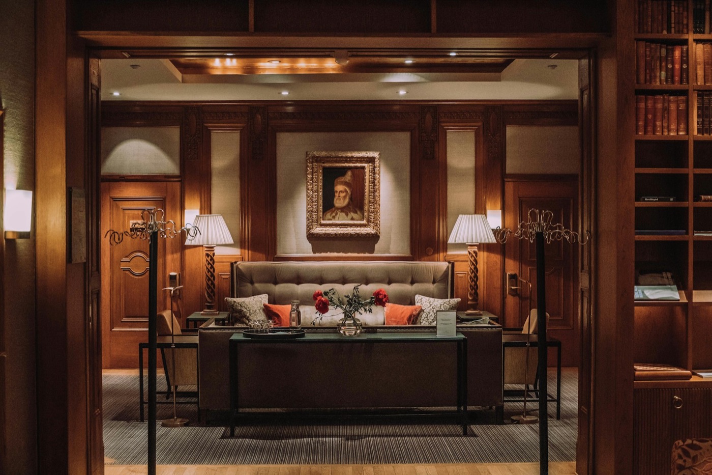 A wood-panelled hotel lounge with a sofa and two lamps