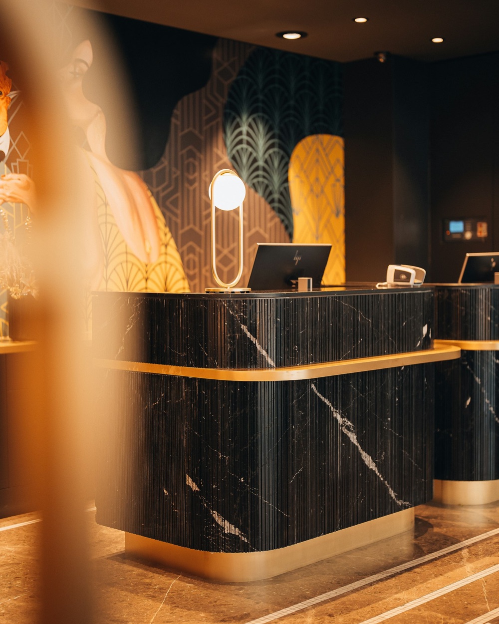 A hotel reception desk in black marble with gold trim